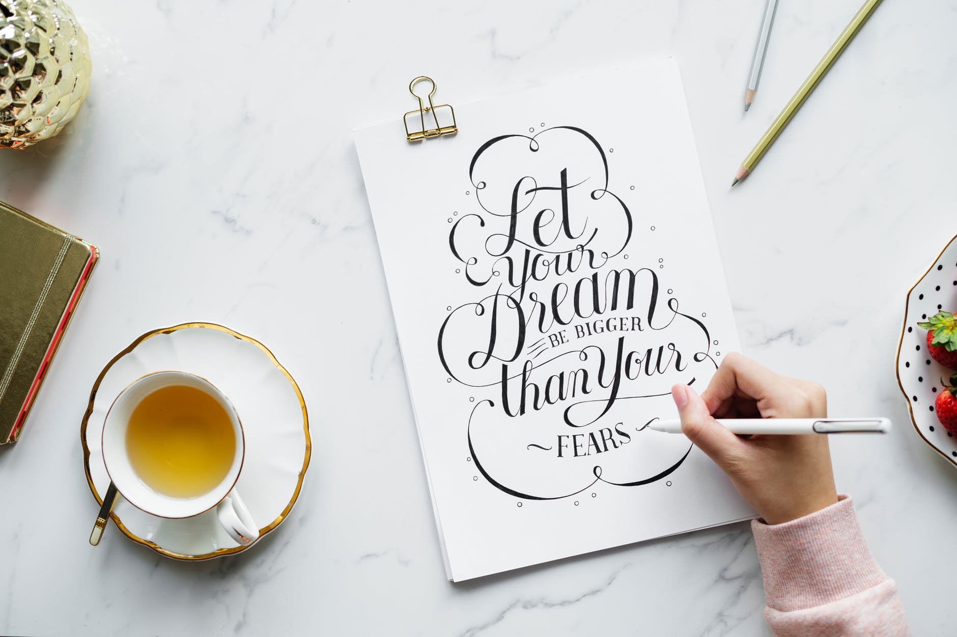 person holding white pen near white poster