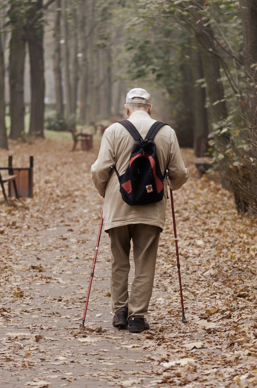 man carrying backpack while walking on a paved pathway